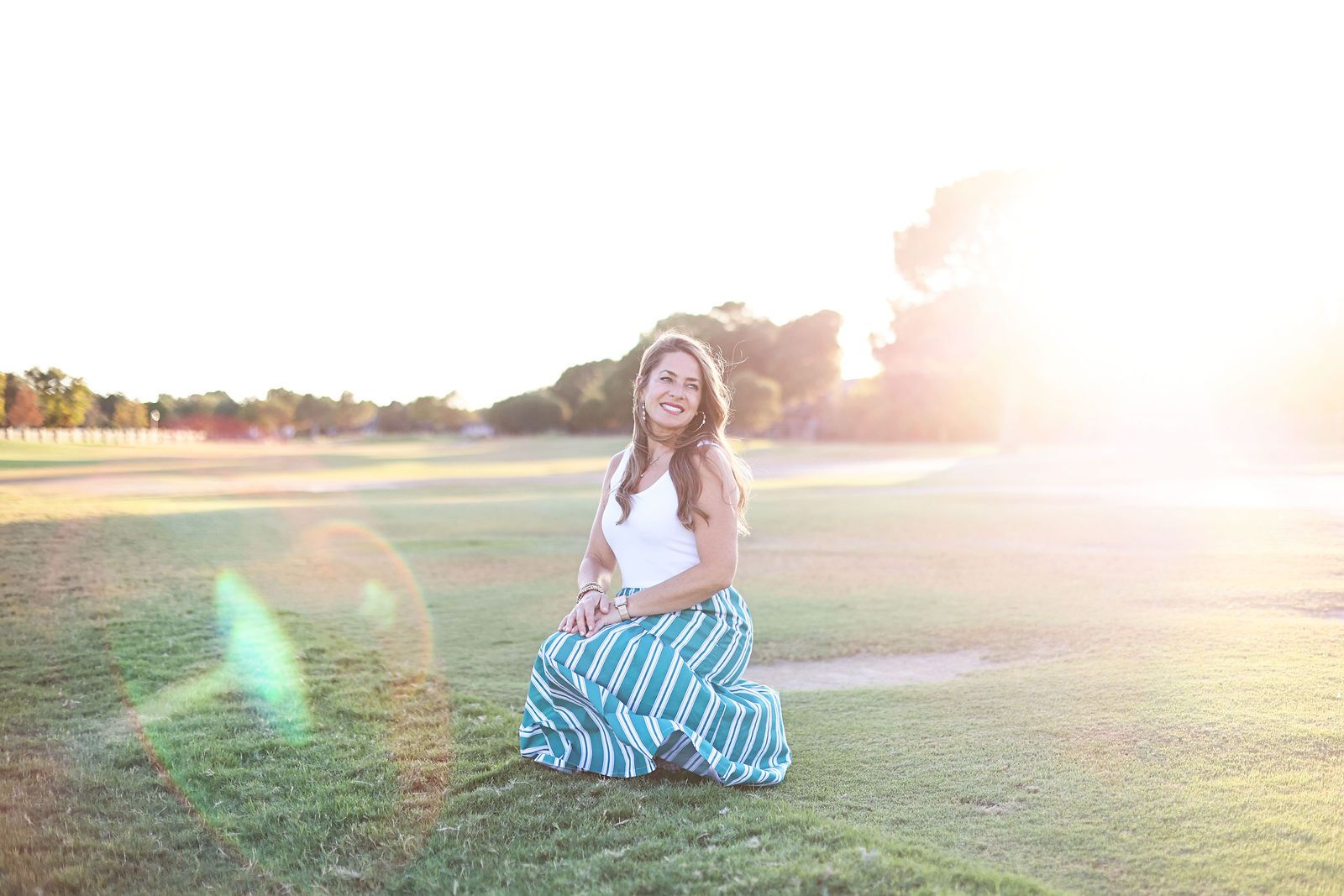 Carrie Gotcher sitting in an open field at sunset